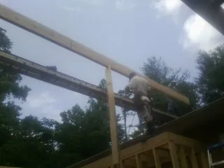 Carpenter setting a ridge beam over a new addition frame — Ice Dam Removal by Roofing Brothers in Southfield
