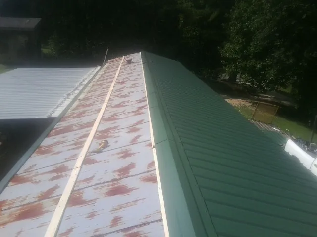 Old rusted panels beside newly installed green metal roofing — Wind Damage Roof Repair by Roofing Brothers in Southfield