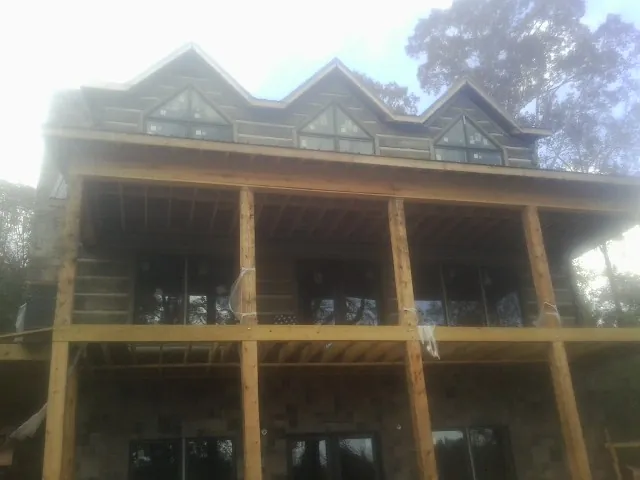 Dormers and porch framing on a large log home under construction — Roof Coating work by our crew in Southfield