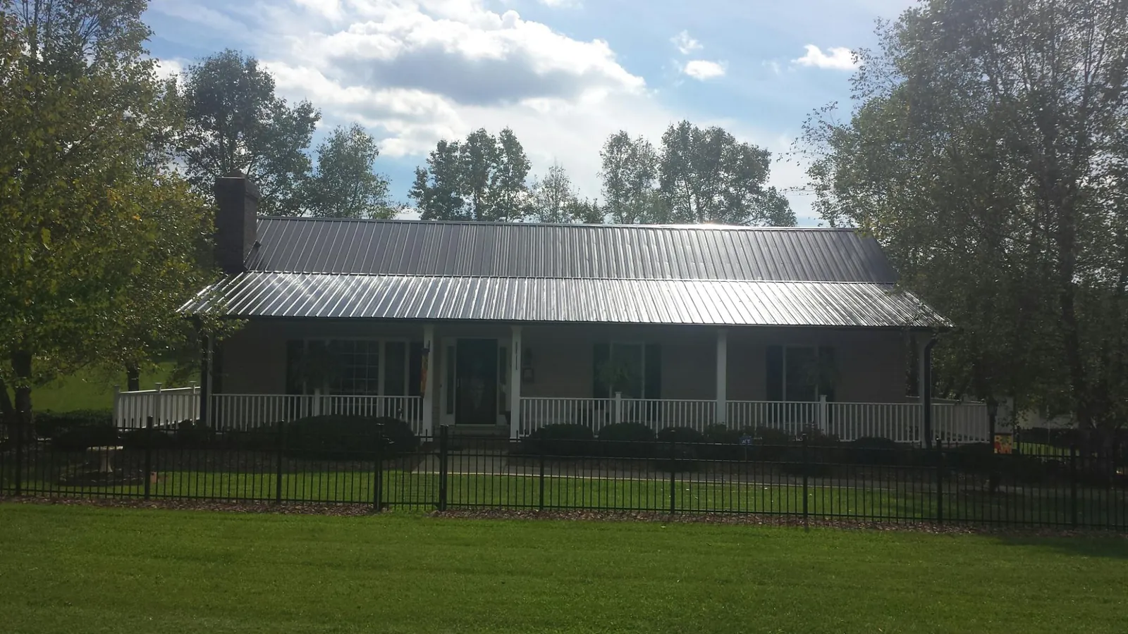 Gray metal roof on a brick ranch with a full width front porch — Gutter Guard Installation work by our crew in Southfield
