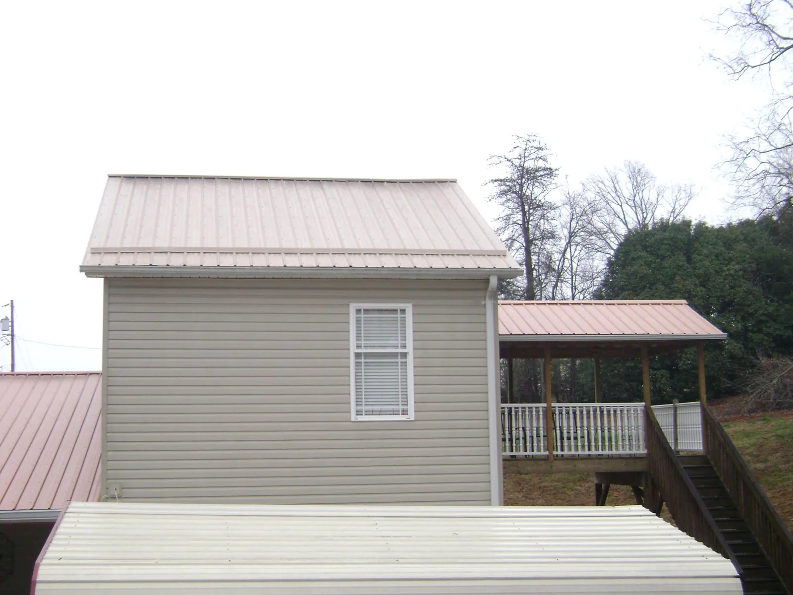 Tan metal roofs on a two story addition and attached porch, from a Roof Replacement job in Southfield