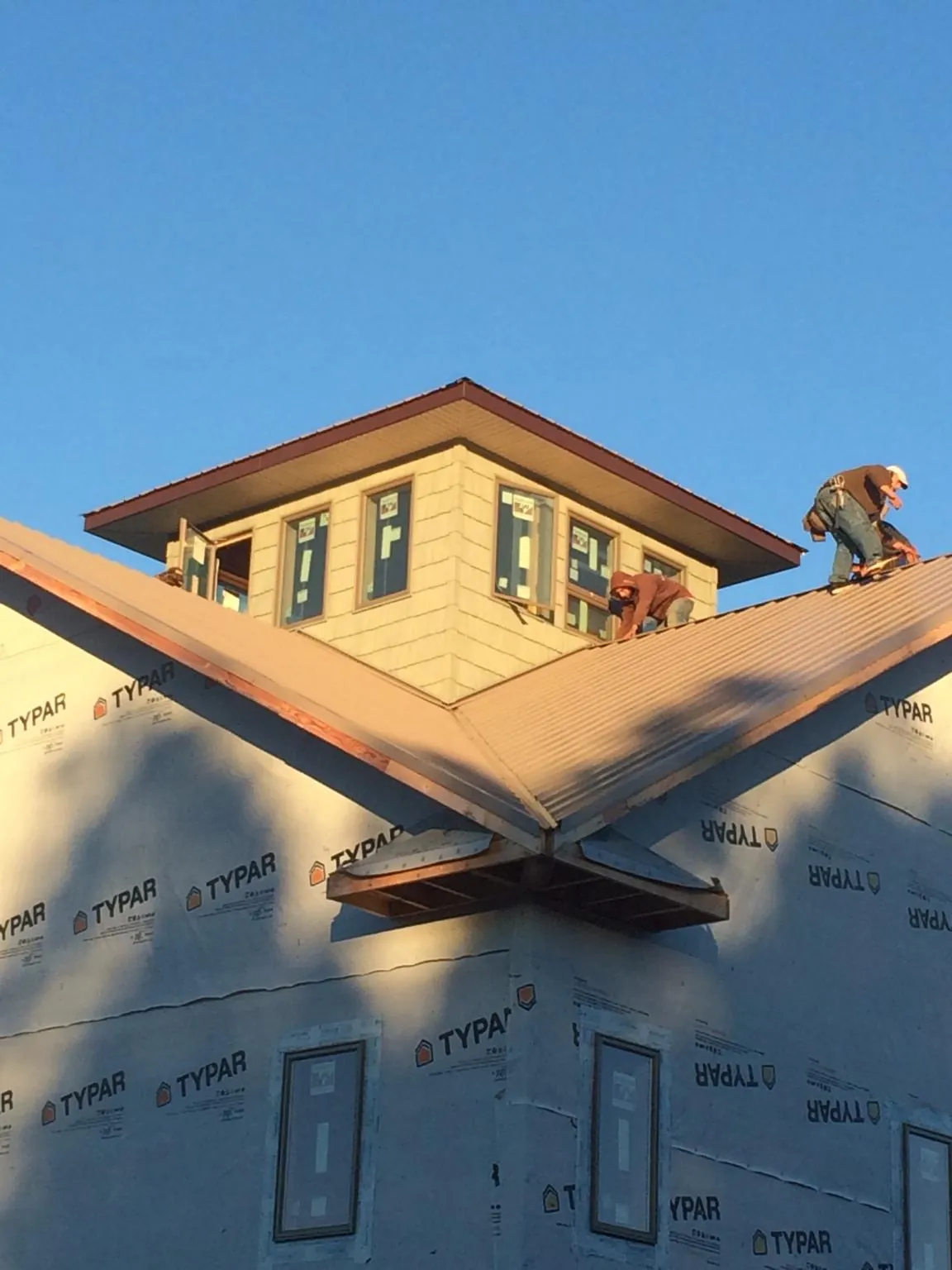 Roofers working around a rooftop cupola on a new metal roof at sunset — Roof Waterproofing in Southfield by Roofing Brothers